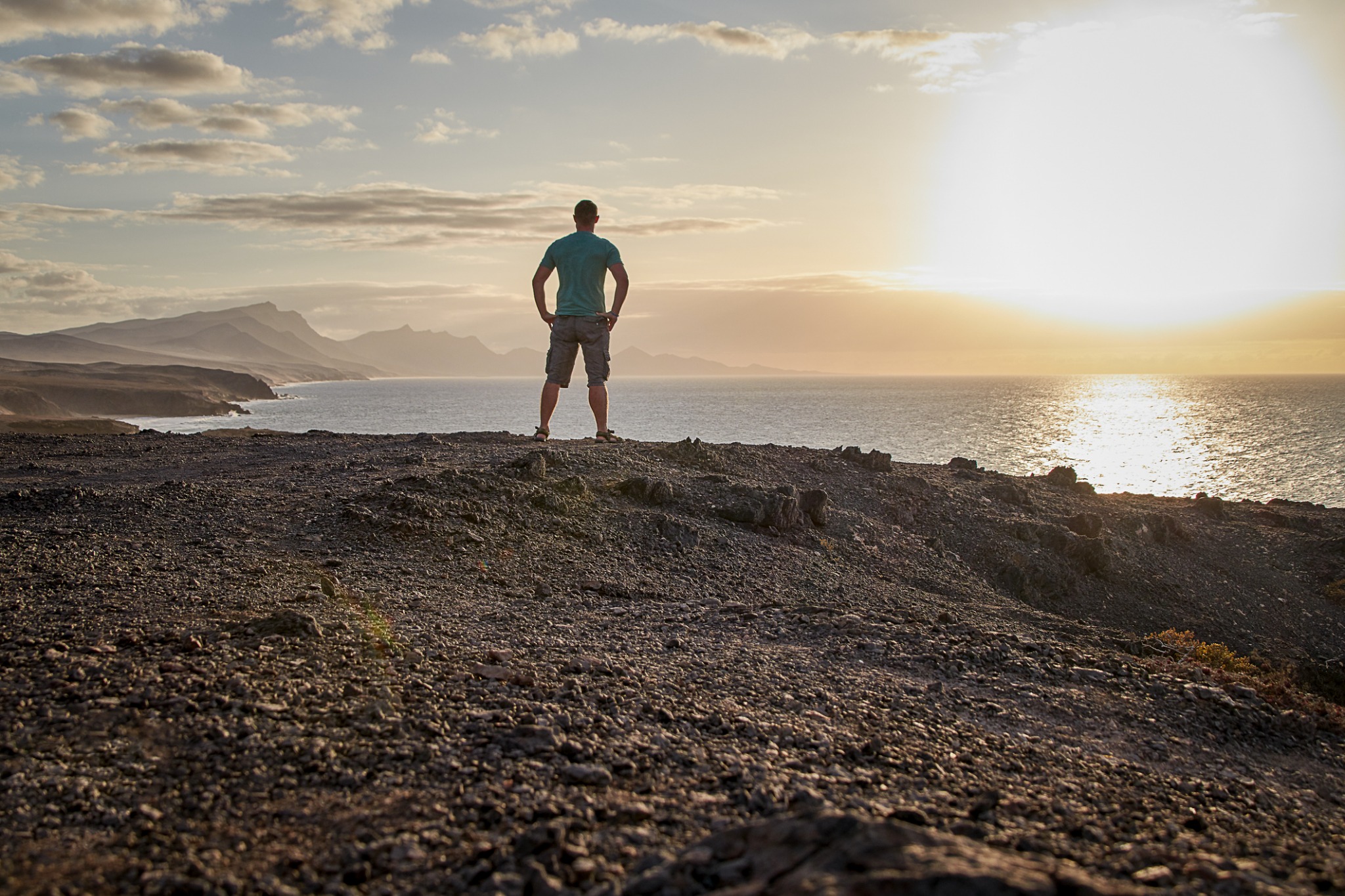 A man standing at the water looking toward the horizon